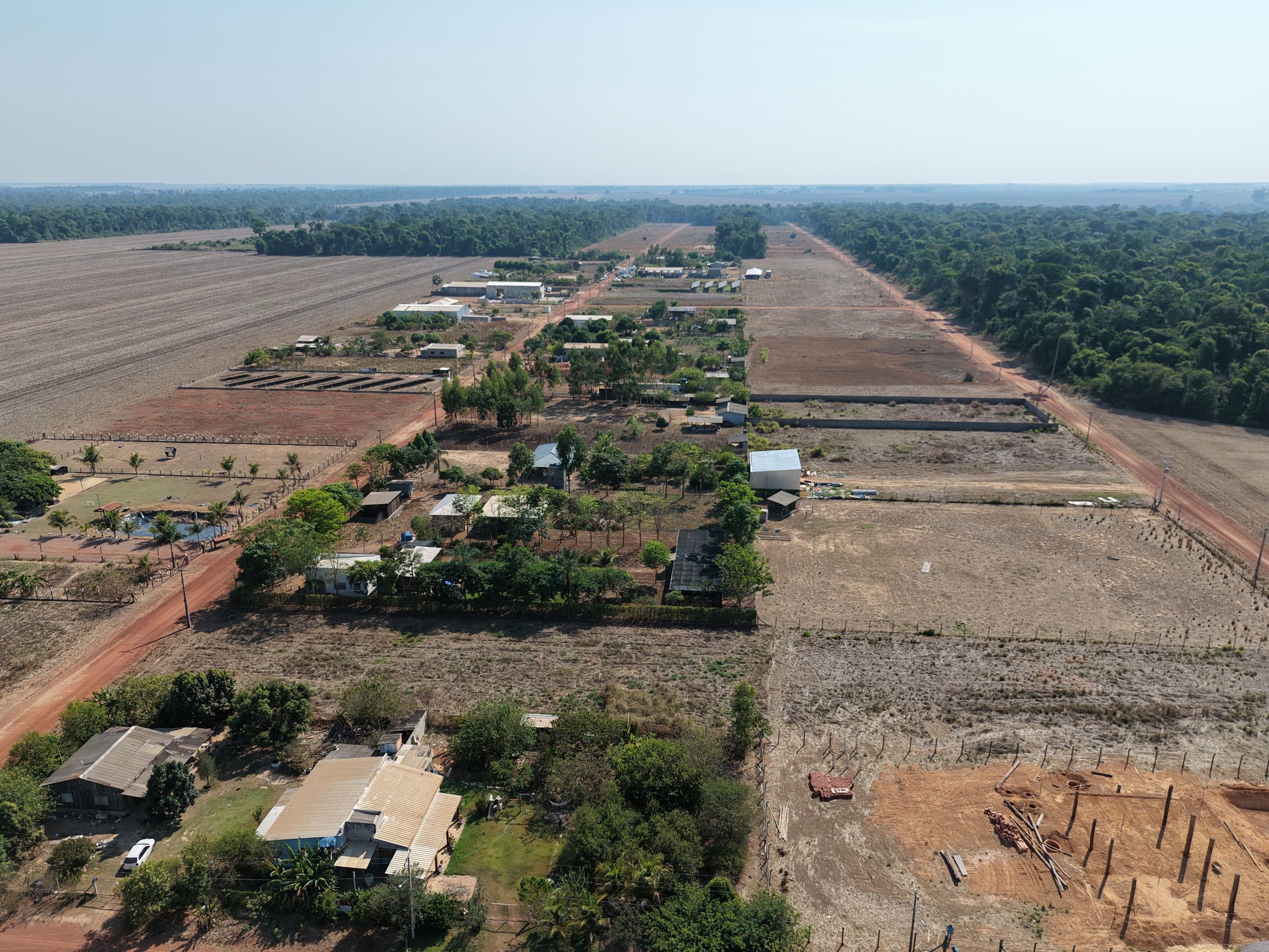 Vista aérea real do Chácaras Nanci: rua de terra com chácaras arborizadas e a mata ao fundo